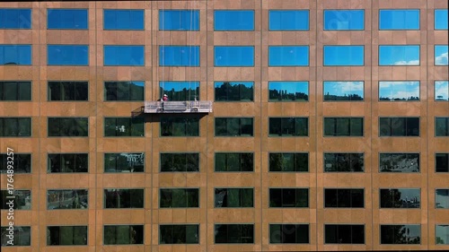 Drone view of workers cleaning windows on high rise building in Los Angeles