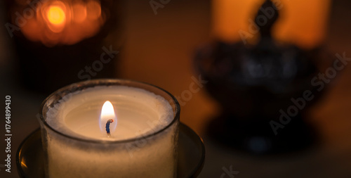 Decoration with candles and other objects in the background. A candle in the foreground.