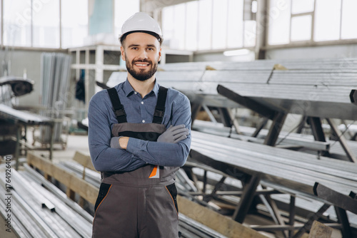 Smiling factory worker posing with crossed arms in aluminum and PVC windows and doors production
