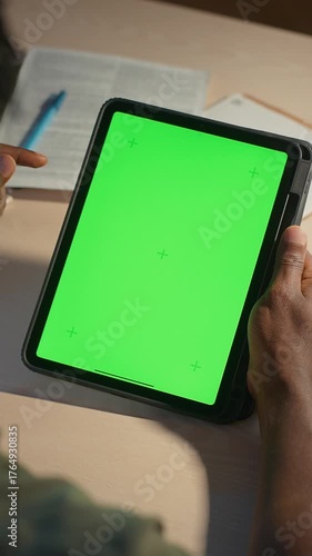 Man scrolling with finger on green screen of tablet at desk