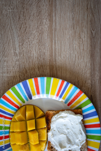 Vibrant breakfast featuring fresh mango slices and creamy toast on a colorful striped plate, perfect for a healthy start.