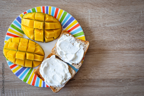 Brightly colored plate holds fresh diced mango and creamy toast spread, perfect for a vibrant breakfast or healthy snack