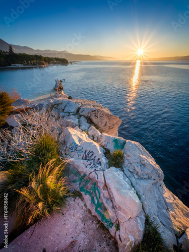 Fototapeta Naklejka Na Ścianę i Meble -  Sunrise over the sea with rocky coast and graffiti.