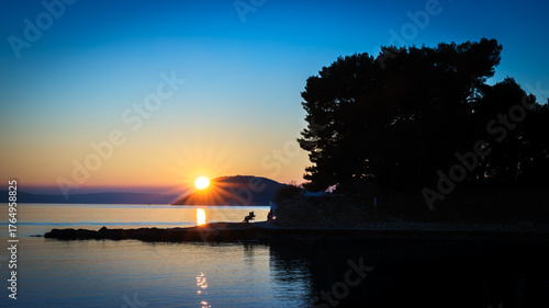 Fototapeta Naklejka Na Ścianę i Meble -  Sunset over the sea with a silhouette of a person.