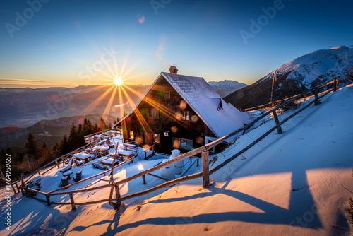 A cozy mountain hut bathed in the warm glow of sunrise.