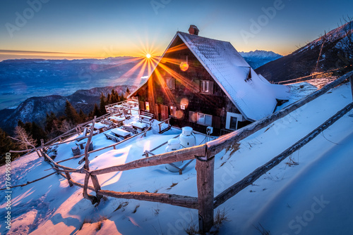 Foto Snowy mountain cabin bathed in golden sunrise light.