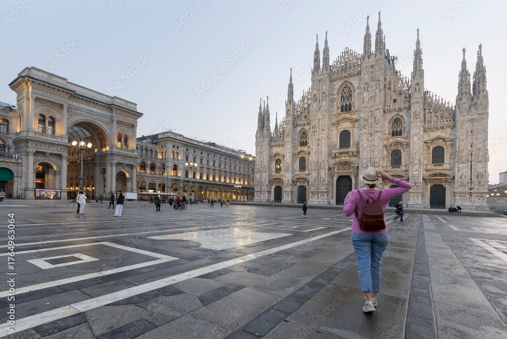Fototapeta premium Holidays in Italy. Rear view of traveler girl holds hat in Milan Cathedral Square, Italy.