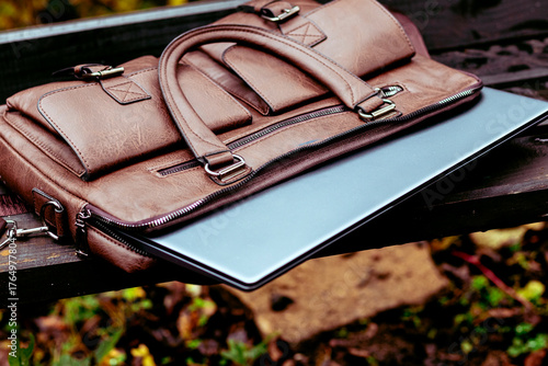 Brown leather bag with laptop left unattended in a park during the afternoon