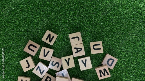 Wooden alphabet tiles scattered across a vibrant green surface