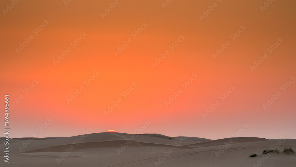Fototapeta premium Dramatic desert sunset with orange sky and sand dunes creates a serene and vast landscape