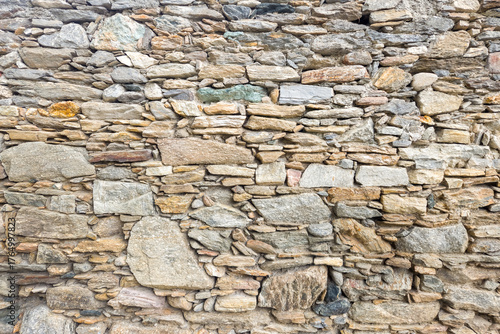 Old stone wall texture made of irregular natural rocks, perfect for rustic architecture, background design, and construction material concepts.