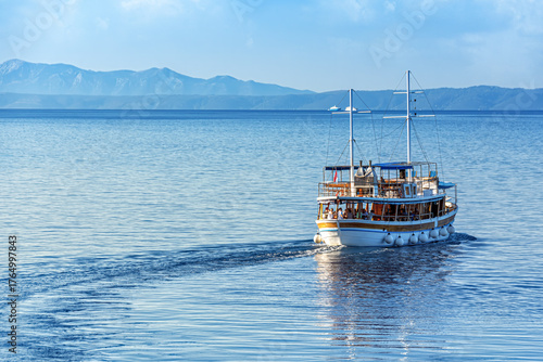 Tourist boat sailing on the blue Adriatic Sea near the Croatian coast on a bright summer day, scenic travel and vacation concept with calm water and mountains.