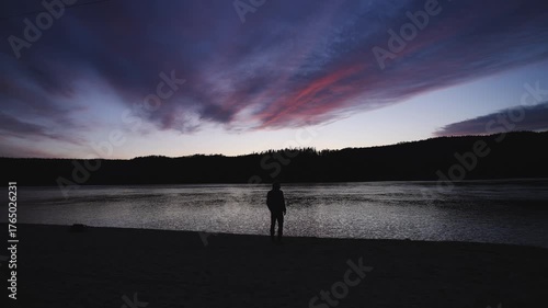 Man in winter clothing walks around a lake during sunset in Northern Norway near Tromso.