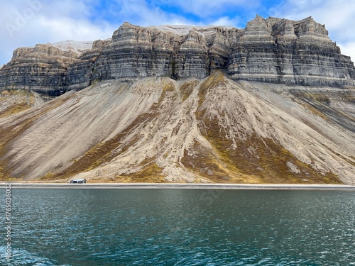 Small cabin is situated beside the ocean with a stunning mountain in Nordre Isfjorden, Spitsbergen, Svalbard