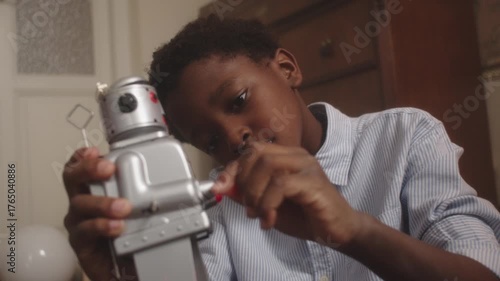 Boy joyfully plays with retro toy robot in cozy indoor setting