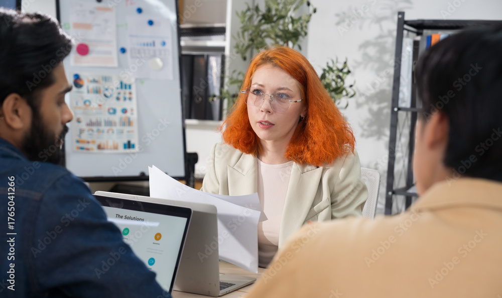 Obraz premium Multi-ethnic business team in office meeting, reviewing documents and brainstorming innovative ideas for a new business venture and strategy.