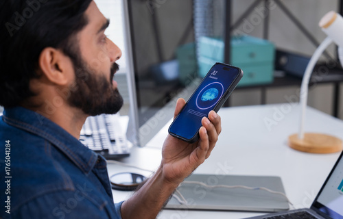 Indian man using AI voice assistant on smartphone in office, interacting with virtual assistant app for productivity, AI-powered speech, and smart technology.