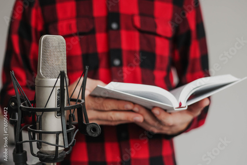 Close up of man flipping through a book near a microphone. Recording audiobook using microphone.