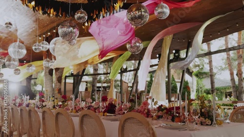 Wedding reception with floral arrangements, flowers, candles, colorful floral arrangements and stunning draperies, as well as disco balls.
