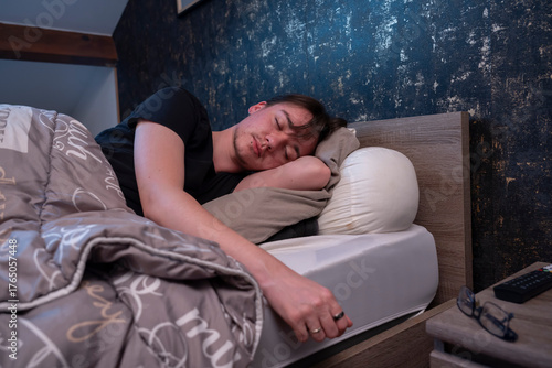 Jeune homme en train de dormir dans son lit, grasse matinée