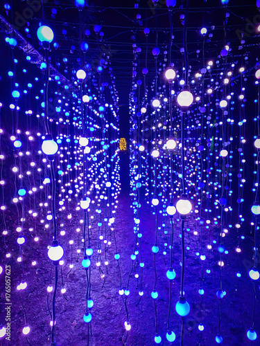 Immersive tunnel filled with blue and white glowing bulbs creating a vibrant light installation at night