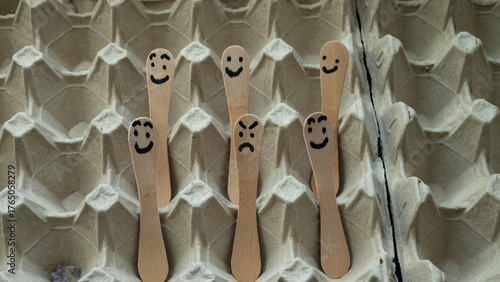 Ice cream sticks with drawn faces in an egg carton.