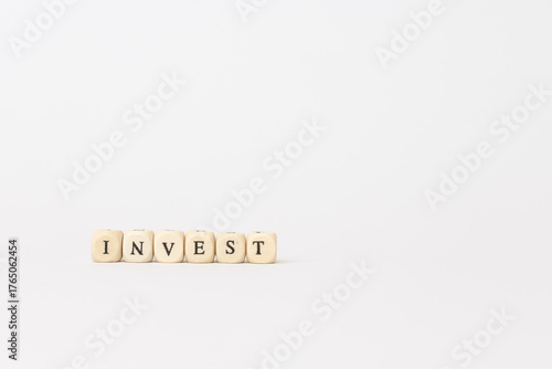 Wooden blocks spelling the word invest on a minimalistic white background, symbolizing finance and investment concepts with copy space. copy space