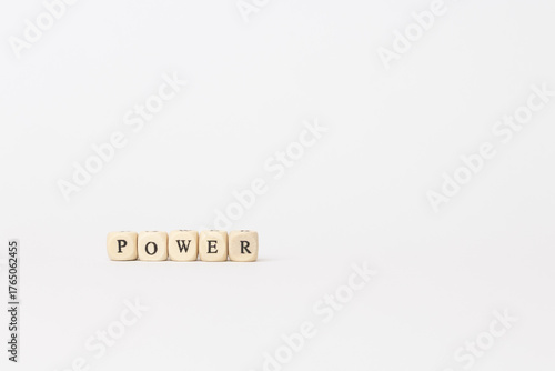 Wooden blocks spelling power on a minimalistic white background, symbolizing strength and influence in finance and technology sectors. copy space