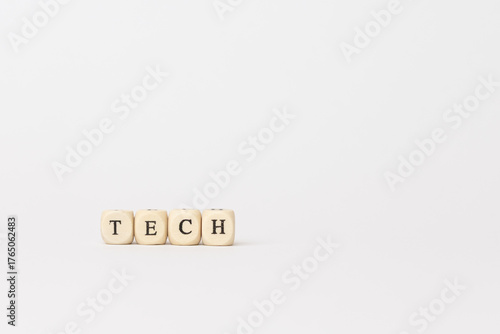 Wooden blocks spelling tech on a minimalistic white background, representing innovation and modern technology concepts in finance. copy space