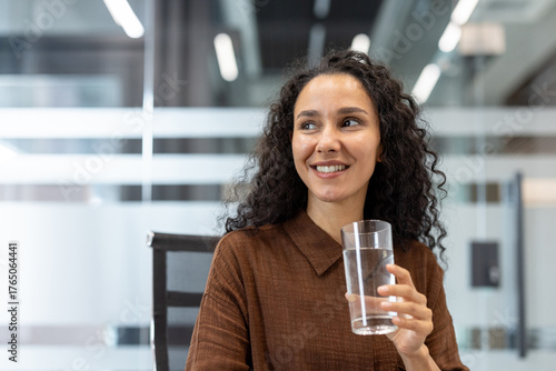 Konstfotografi Woman smiling while staying hydrated at her modern office desk, enjoying a refre