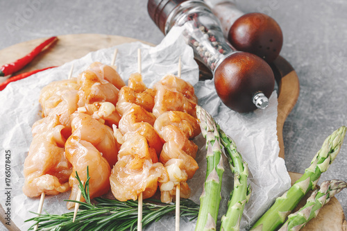 Raw turkey breast kebab. Raw cut turkey breast on wooden skewers with asparagus and sauce is ready to be cooked. Close-up