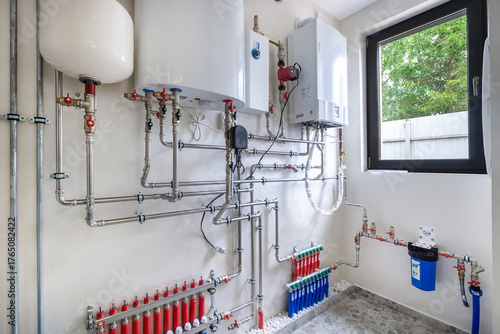 A complex plumbing system is visible in this residential utility room. Tanks and pipes are neatly arranged, showcasing modern heating and water solutions for the home.