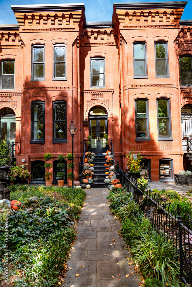 Fototapeta premium Leaf-strewn path leading to a vintage-style townhouse door. classic East Coast architecture during peak fall season.