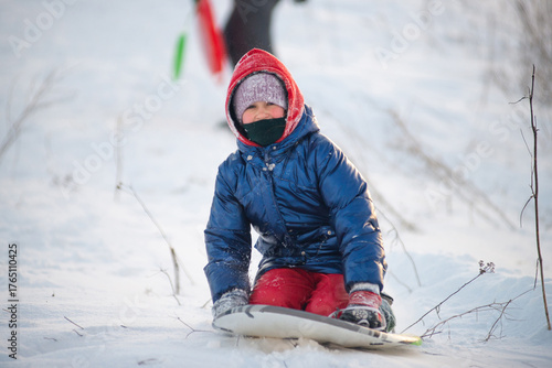 Happy child rides a sled down a snowy slope