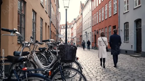 Rear View of Couple Walking on Cobblestone Street Lined with Bicycles and Colorful Buildings in Copenhagen Denmark Under a Cloudy Sky in the Daytime