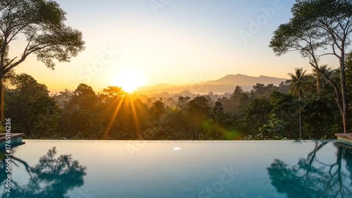 Serene Jungle View from Infinity Pool during Sunrise with Hazy Mountains, Reflections in Blue Water, Green Foliage, and Golden Light, Tropical Paradise