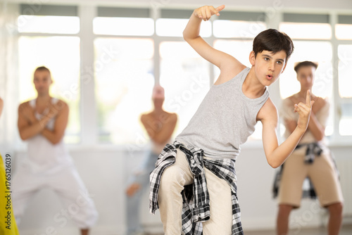 Tableau sur toile Positive teenage boy dancing hip-hop standing with her back to group members dur
