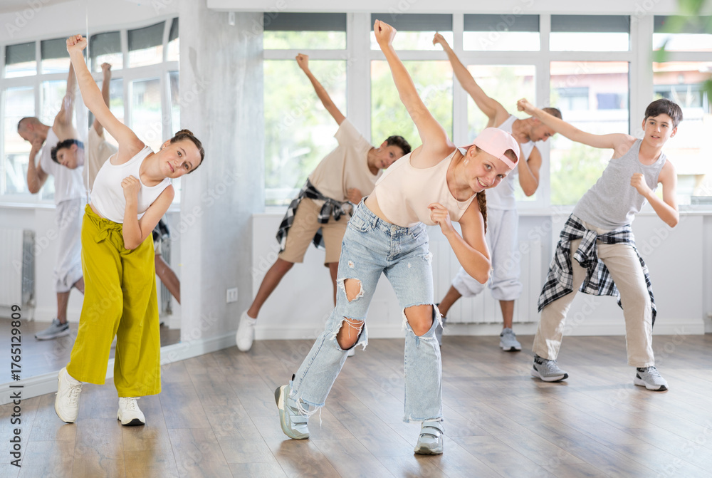 Naklejka premium Teen girl dancing hip hop in group of teenagers in dance studio