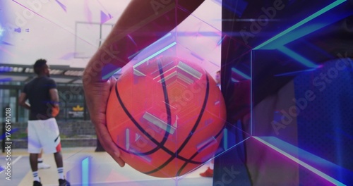 Athletic player wearing dark jersey holding basketball at urban court, with neon overlays and hoop