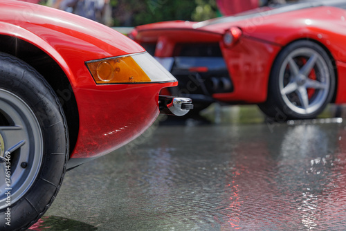 Classic sports car's style and grace accentuated by reflecting waters of shallow pool, highlighting smooth flowing contours of the vibrant red body's aerodynamic design.