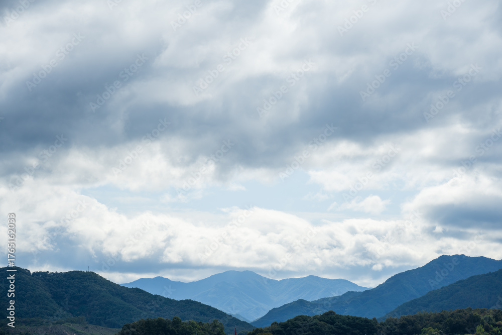 Obraz premium Layered mountain landscape under cloudy sky