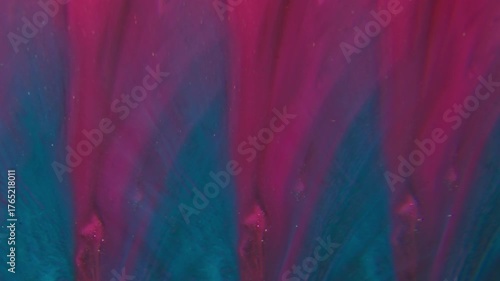 Ink stream. Neon background. Defocused purple pink blue colorful glitter flow particles spreading on creative acrylic abstraction.