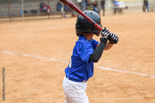 A 6 to 7 year old boy practicing batting while waiting for his turn to bat on the ballfield. Kids baseball game.