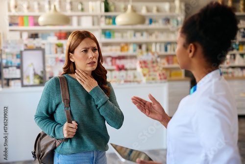 Worried woman complaining of sore throat while talking to pharmacist.