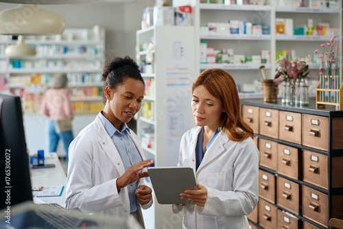 Female pharmacists using digital tablet while working in pharmacy.