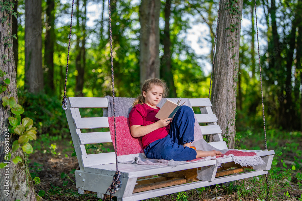 Fototapeta premium Child playing and dreaming on swing outside. Happy child enjoying playful activity in garden. Young kid sitting calmly on swing in nature. Child enjoying freedom and fun on backyard swing.