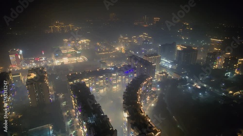 aerial drone flying over brightly lit and decorated buildings for diwali with fireworks going all around with delhi cityscape in distance with smoke smog fog pollution over Delhi, Gurgaon, Noida