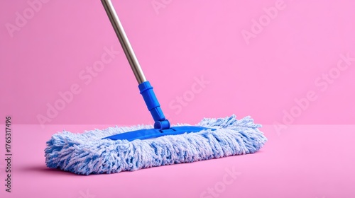 Blue mop with metallic handle against a bright pink background