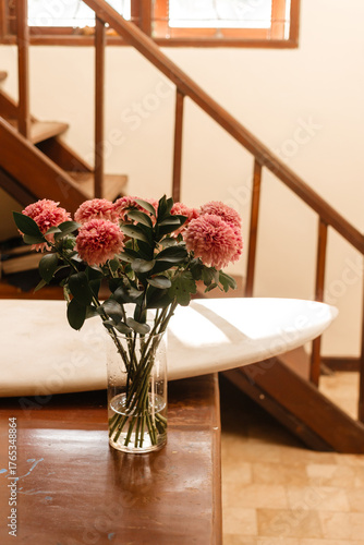 Pink chrysanthemums in a glass vase on a background of white surfboard. Flowers in the surfer living room. Bouquet of flowers in the interior of the house