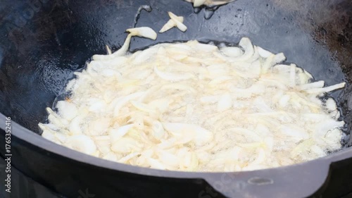 chopped onions are fried in oil in a cauldron